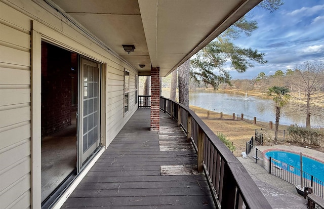 wooden deck featuring a fenced in pool and a water view