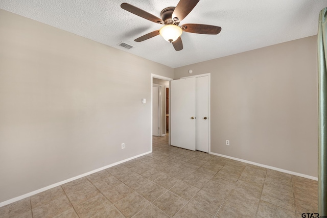 unfurnished bedroom with a textured ceiling, a closet, a ceiling fan, and baseboards