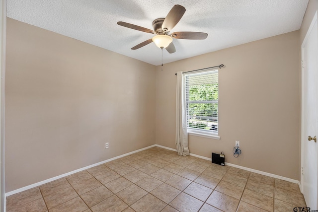 empty room with a textured ceiling, ceiling fan, light tile patterned flooring, and baseboards