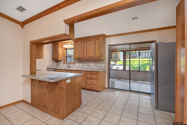 kitchen featuring freestanding refrigerator, a sink, crown molding, light tile patterned floors, and tasteful backsplash