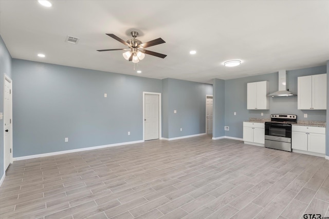 kitchen with white cabinets, wall chimney range hood, stainless steel range with electric stovetop, and light wood-type flooring