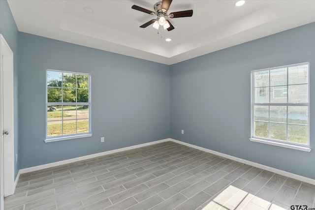 empty room featuring light wood-type flooring, ceiling fan, and a raised ceiling