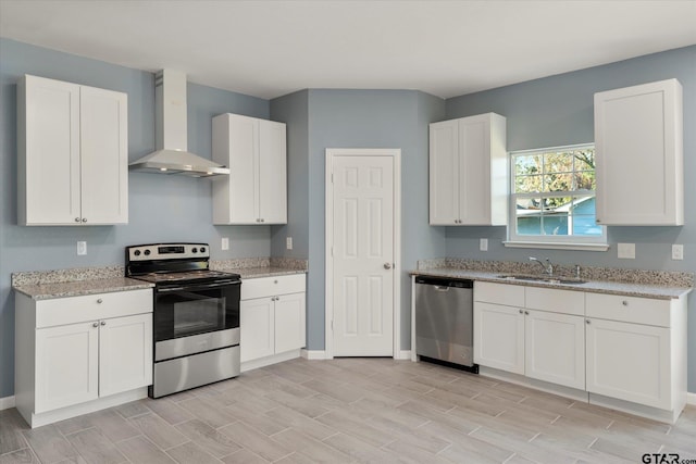 kitchen with stainless steel appliances, wall chimney exhaust hood, white cabinetry, and light hardwood / wood-style flooring