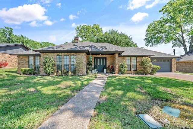 view of front of house with concrete driveway, a chimney, a front yard, brick siding, and a garage