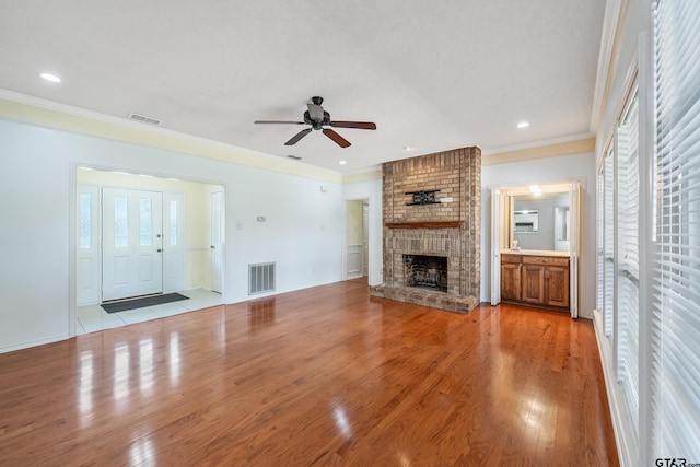 6214 Huntington Dr, Tyler, TX 75703 - unfurnished living room featuring a fireplace, ceiling fan, healthy amount of natural light, light wood finished floors, and ornamental molding