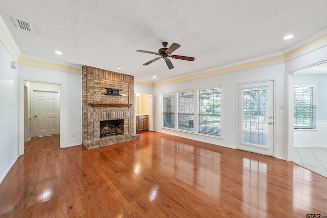 6214 Huntington Dr, Tyler, TX 75703 - unfurnished living room featuring a ceiling fan, a textured ceiling, ornamental molding, a fireplace, and wood finished floors