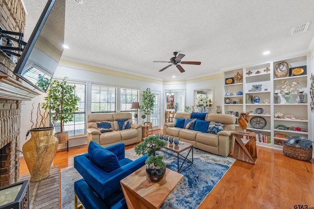 living area with a textured ceiling, wood finished floors, ceiling fan, and visible vents