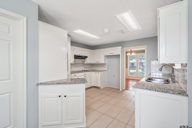 6214 Huntington Dr, Tyler, TX 75703 - kitchen with a sink, decorative backsplash, white cabinetry, and a textured ceiling