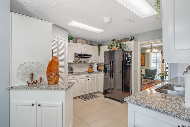 kitchen featuring under cabinet range hood, tasteful backsplash, white cabinetry, and black appliances