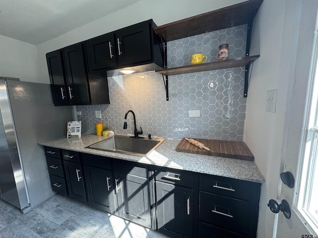 1314 N Queen St, Palestine, TX 75803 - kitchen featuring light stone counters, dark cabinets, backsplash, a sink, and freestanding refrigerator