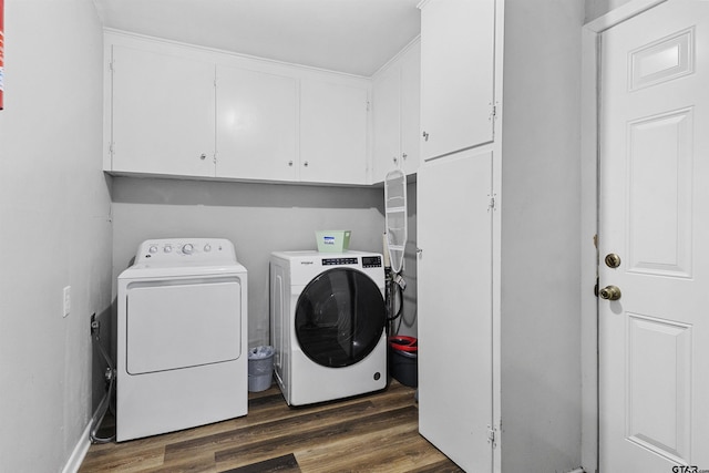 clothes washing area featuring cabinets, washing machine and clothes dryer, and dark hardwood / wood-style floors