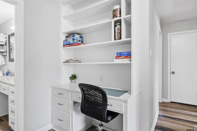 home office with built in desk and dark hardwood / wood-style floors