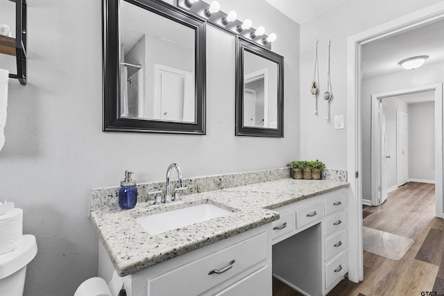 bathroom with hardwood / wood-style flooring, toilet, and vanity