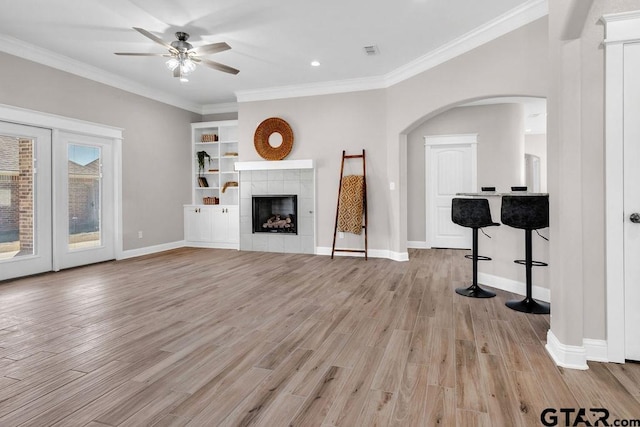 unfurnished living room with baseboards, light wood finished floors, crown molding, and a tile fireplace