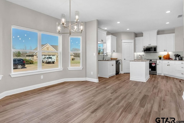 kitchen with light wood finished floors, baseboards, backsplash, and stainless steel appliances