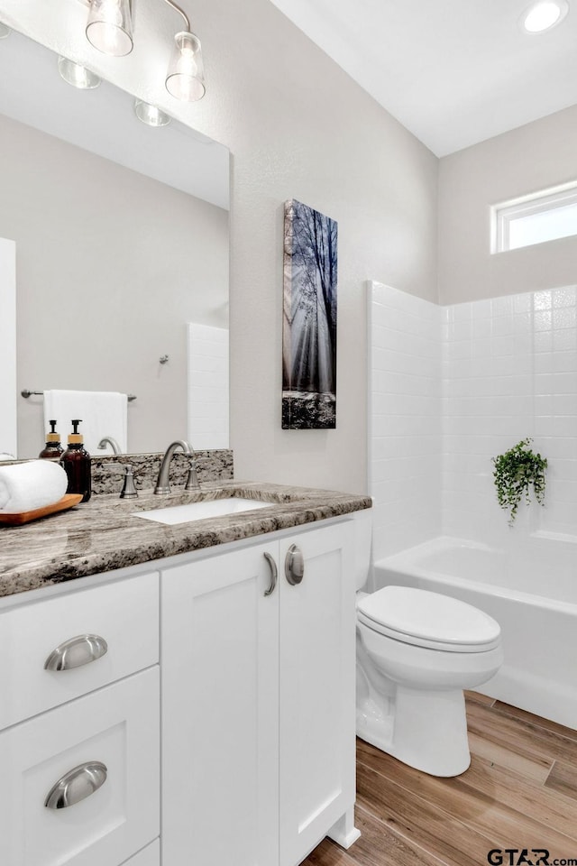 bathroom featuring vanity, toilet, wood finished floors, and shower / bath combination