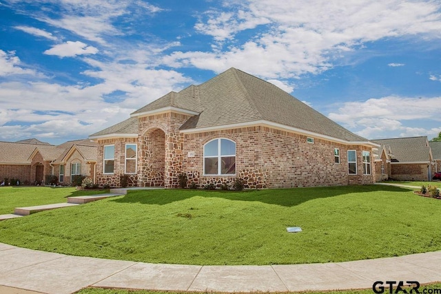 french country inspired facade featuring a front lawn, brick siding, and a shingled roof