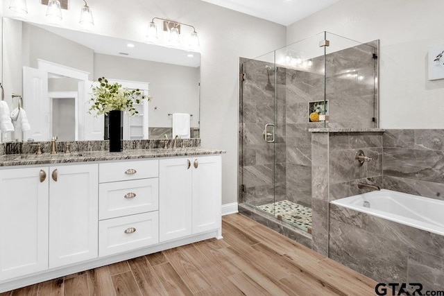 bathroom featuring a sink, a garden tub, wood finished floors, and a shower stall