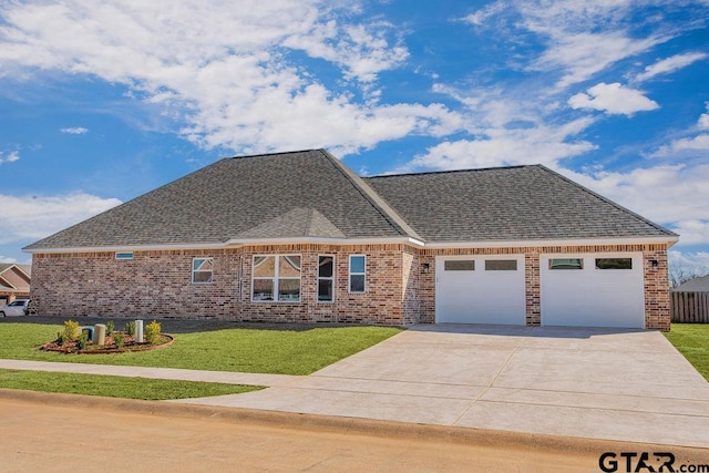 view of front of house featuring a front yard, driveway, a shingled roof, a garage, and brick siding