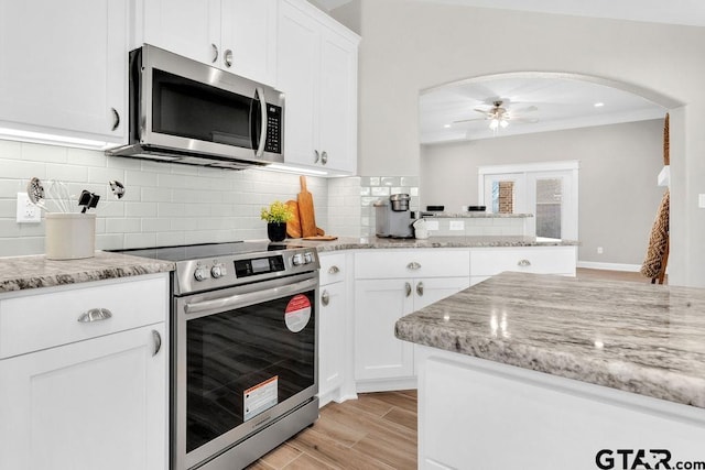 kitchen featuring ceiling fan, light stone counters, decorative backsplash, appliances with stainless steel finishes, and white cabinets