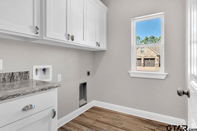 clothes washing area featuring cabinet space, hookup for a washing machine, baseboards, and wood finished floors