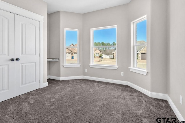 unfurnished bedroom featuring a closet, baseboards, and dark carpet