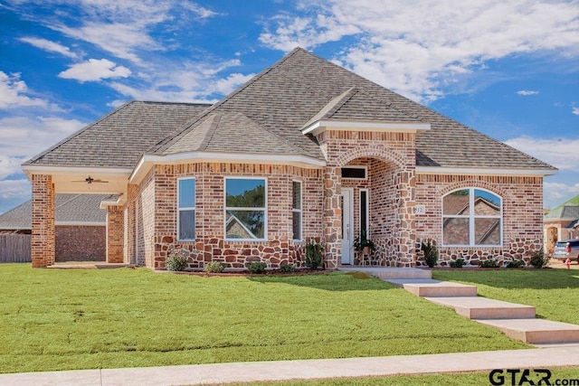 french country inspired facade featuring brick siding, roof with shingles, and a front yard