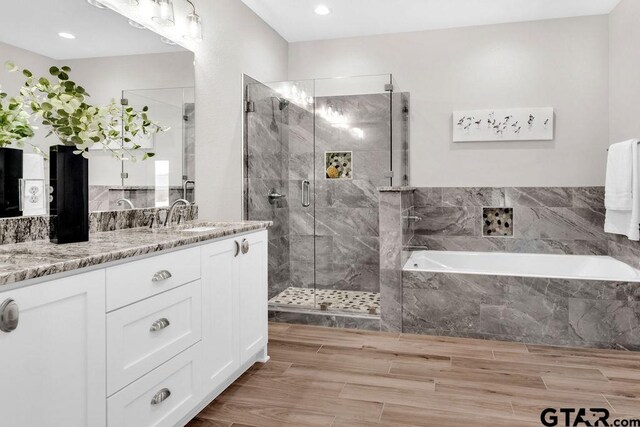 bathroom featuring vanity, a shower stall, a bath, and wood tiled floor