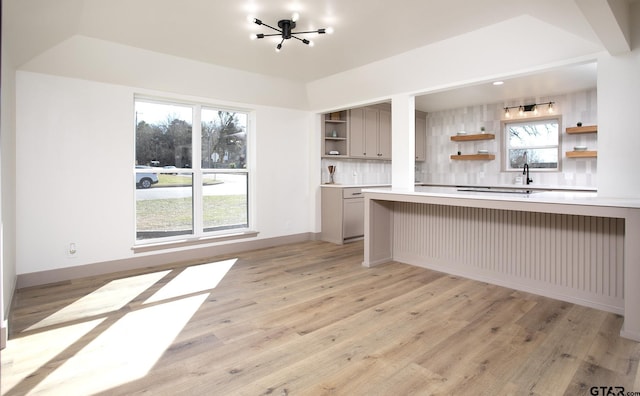 kitchen featuring tasteful backsplash, a kitchen breakfast bar, sink, and light wood-type flooring