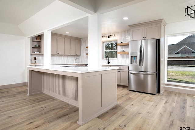 kitchen with tasteful backsplash, sink, gray cabinetry, stainless steel fridge, and light hardwood / wood-style flooring