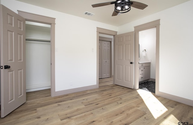 unfurnished bedroom featuring ceiling fan, a closet, connected bathroom, and light hardwood / wood-style flooring