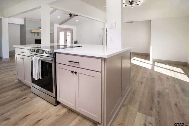 kitchen with stainless steel electric stove, white cabinetry, beam ceiling, a center island, and light wood-type flooring