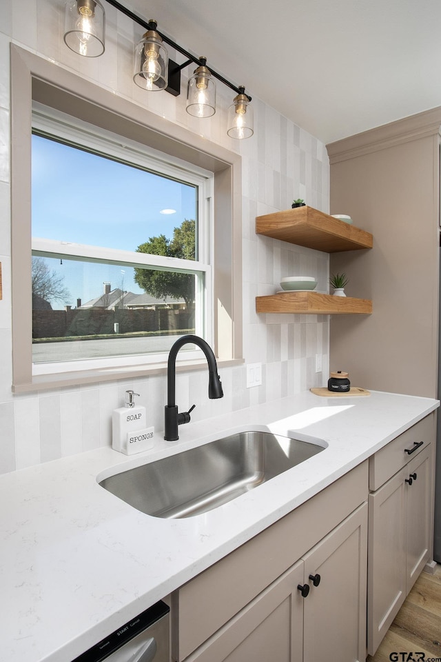 kitchen with sink, dishwasher, ornamental molding, light stone countertops, and decorative backsplash