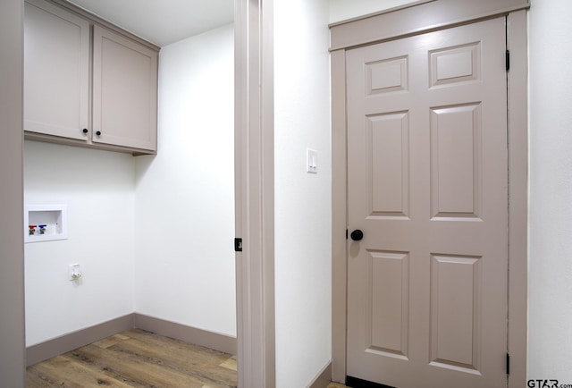 washroom featuring hookup for a washing machine, light wood-type flooring, and cabinets