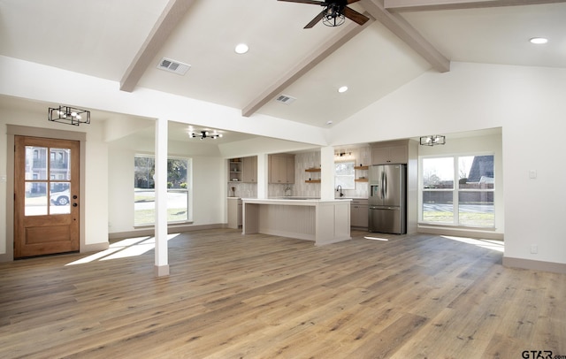 unfurnished living room with a healthy amount of sunlight, high vaulted ceiling, light wood-type flooring, and beam ceiling