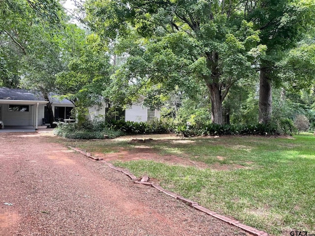 1106 E Redbud, Crockett, TX 75835 - view of green lawn with an attached carport and dirt driveway
