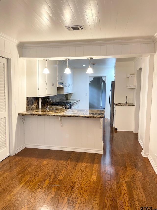 1106 E Redbud, Crockett, TX 75835 - kitchen with ornamental molding, dark stone counters, a peninsula, dark wood-type flooring, and pendant lighting