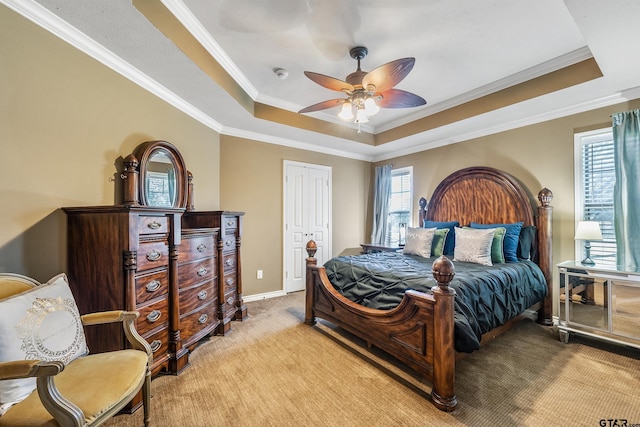 carpeted bedroom with a closet, a raised ceiling, ceiling fan, and crown molding