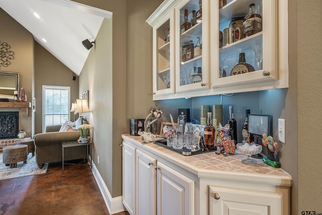 bar featuring white cabinets and vaulted ceiling