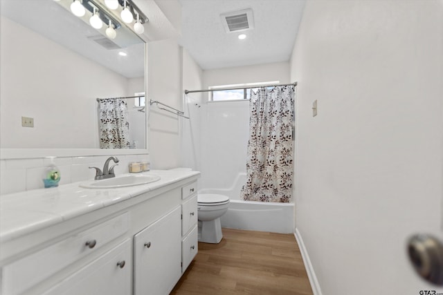 bathroom featuring visible vents, baseboards, toilet, wood finished floors, and vanity