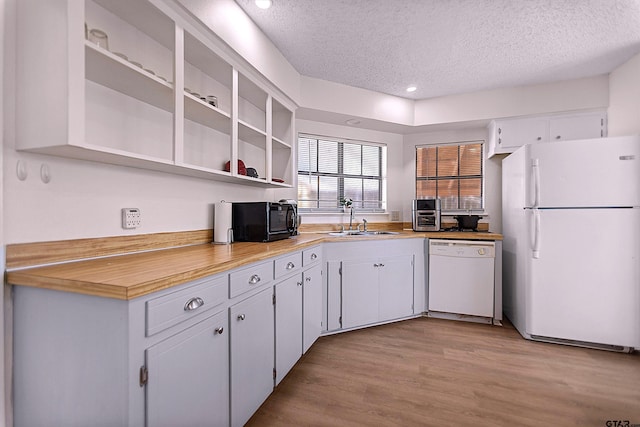 kitchen featuring a sink, light wood-type flooring, white appliances, white cabinetry, and open shelves