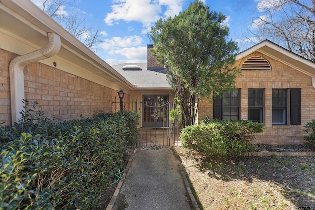 doorway to property with brick siding, a chimney, and a gate