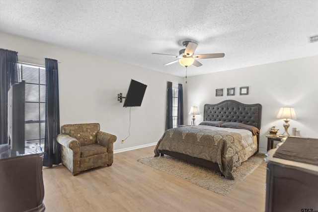 bedroom with visible vents, a textured ceiling, light wood-style flooring, and a ceiling fan