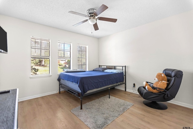 bedroom with a textured ceiling, baseboards, and wood finished floors