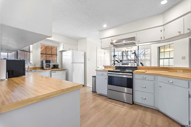 kitchen featuring range hood, light wood-style floors, white appliances, a textured ceiling, and a sink