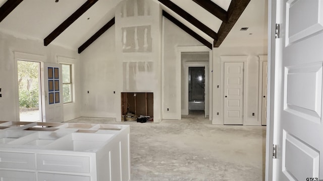 unfurnished living room with beam ceiling and high vaulted ceiling