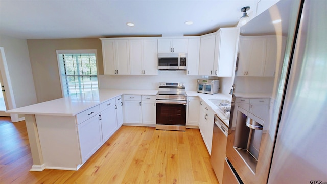 15269 County Road 1227, Flint, TX 75762 - kitchen with appliances with stainless steel finishes, light wood-type flooring, a peninsula, light countertops, and white cabinets