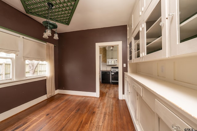 unfurnished dining area with baseboards and dark wood finished floors