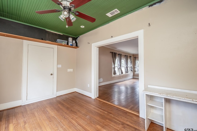 interior space featuring baseboards, visible vents, wood finished floors, and ceiling fan