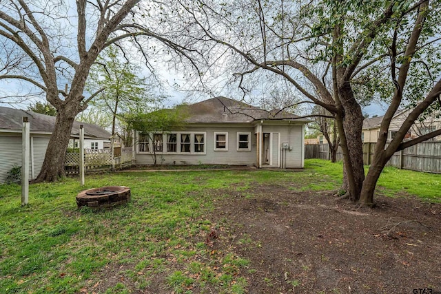 rear view of property with fence private yard, a fire pit, and a lawn